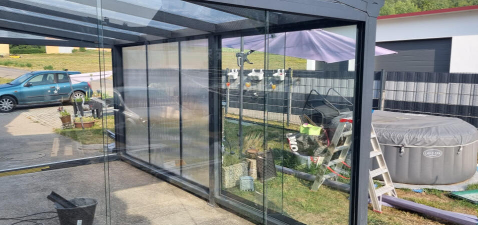 Glasschiebeelemente für Terrassenüberdachung Rahmenlose Glasschiebeelemente als seitlicher Wetterschutz einer Terrassenüberdachung