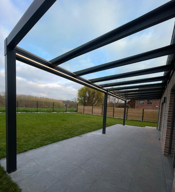 Terrassenüberdachung aus Aluminium Großzügige Terrassenüberdachung mit dunkler Aluminiumkonstruktion und transparentem Dach
